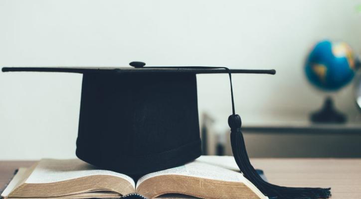 Imatge de recurs. Llibres i un barret de graduat